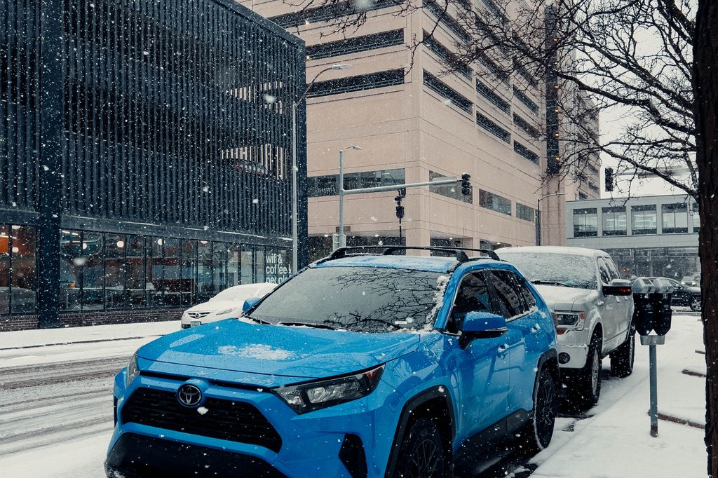 An SUV parked on a snow-covered city street during a winter snowfall