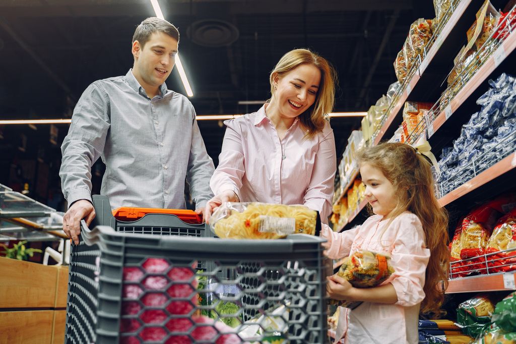 A family shopping together in a supermarket aisle with a cart