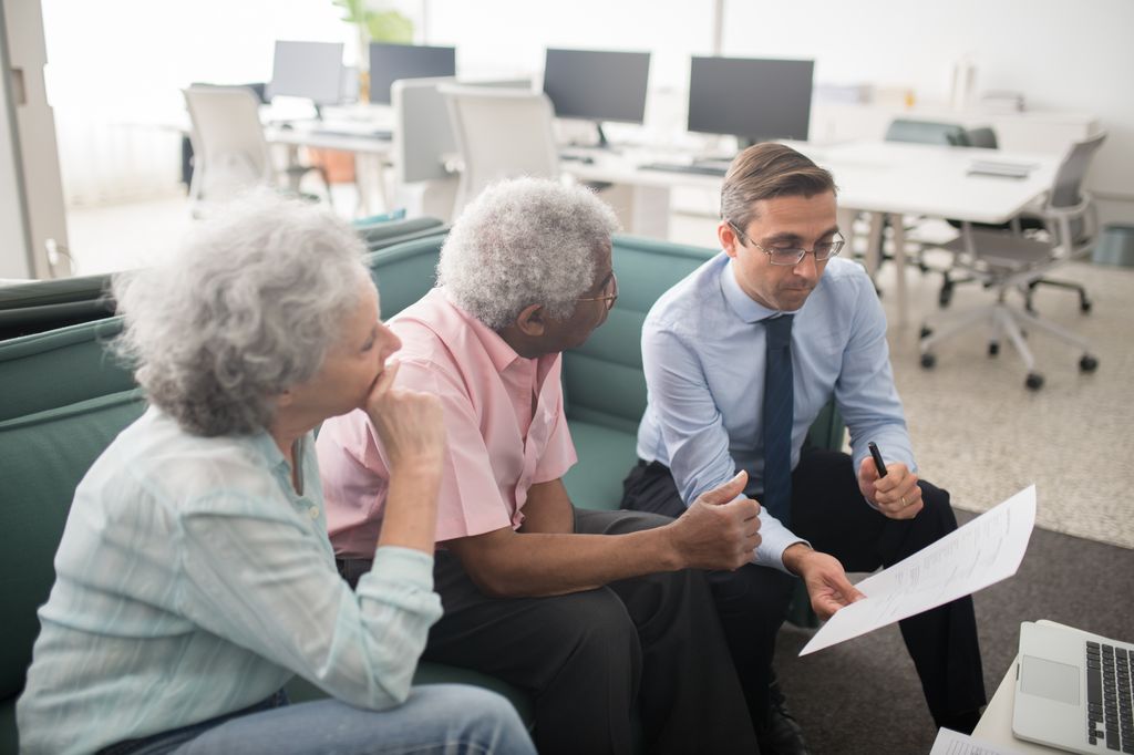 A financial advisor reviewing documents with two clients in an office
